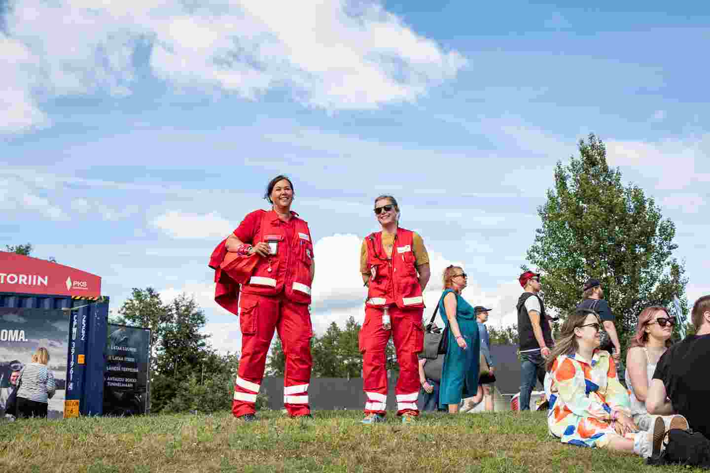 Röda Korsets första hjälpen-jourhavande ler mot kameran i en solig festivalmiljö.