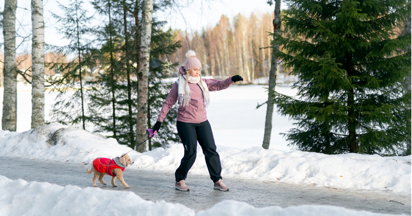 En kvinna promenerar med sin hund på en hal friluftsled.